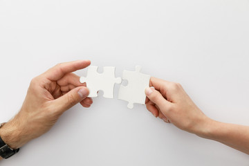 cropped view of woman and man holding pieces of jigsaw puzzle on white background