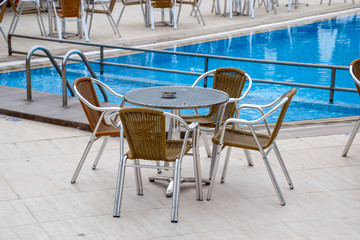 Metal tables and chairs with wicker seats in outdoor cafe.
