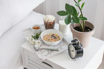 Tray with tasty breakfast on bedside table