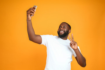 Happy African-American man taking selfie on color background