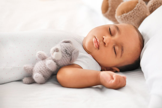 Cute African-American baby sleeping on bed