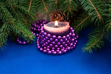 Candle burns near Christmas tree branches and cones. Background for New Year and Christmas.
