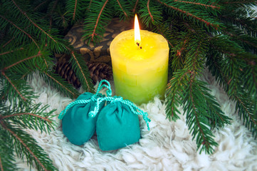 Candle burns near Christmas tree branches and cones. Background for New Year and Christmas.