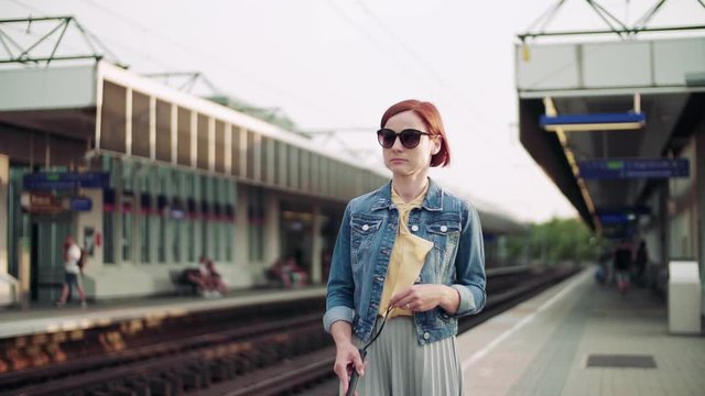 Young blind woman commuter with white cane walking outdoors in city.
