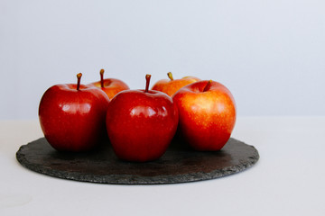 Several red apples on a black plate on a white background. Conceptually on the topic of healthy eating, veggie and diet