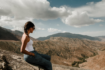 brunette girl with sunglasses looking towards the valley of the high atlas