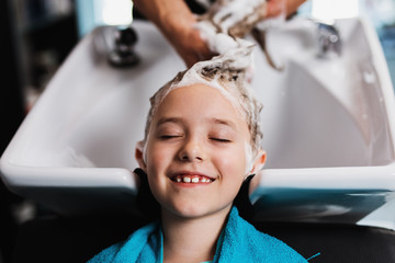 Beautiful little girl at hairsalon. Hair washing.