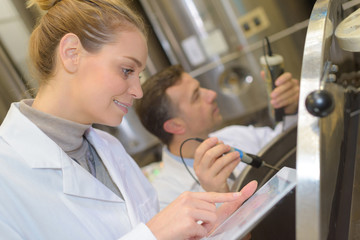 smiling woman with digital tablet by vat in brewery