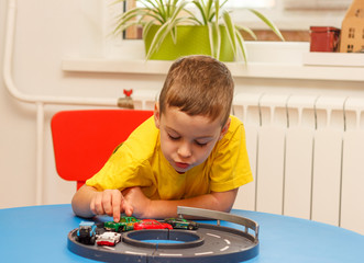 Little boy in yellow t-shirt playing with cars and toys at home, indoor