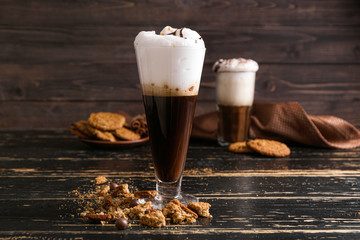 Glass of tasty frappe coffee and sweets on table