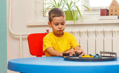 Little boy in yellow t-shirt playing with cars and toys at home, indoor