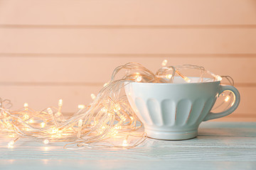 Cup with Christmas lights on wooden table