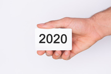 Welcome 2020 . Hand holding a white card . White background. Copy space