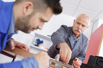 old carpenter with apprentice in training period