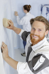 professional man using sponge float on wall