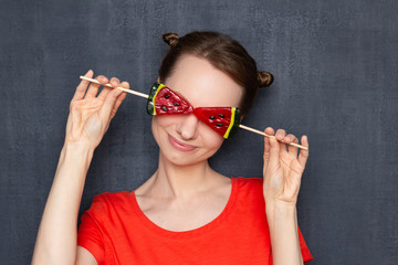 Portrait of cute happy young woman covering eyes with lollipops