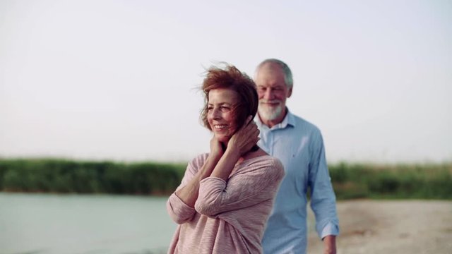 Senior couple on a holiday on a walk by the lake, hugging. Slow motion.