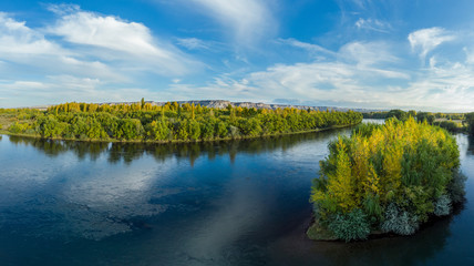 Panoramic view of a river valley in autumn. The yellow tone is observed in the vegetation it makes contrast with the river and the mountains behind. General Roca, Río Negro - Patagonia Argentina