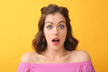 Surprised young woman on color background