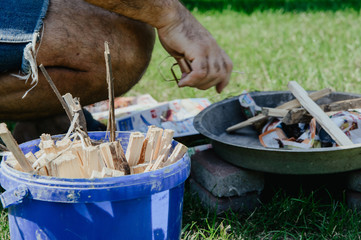 Obraz premium Lighting a bonfire. The concept of spending free time outdoors. Lighting a bonfire made of wood. Safe lighting a bonfire, roasting sausages, making a barbecue.