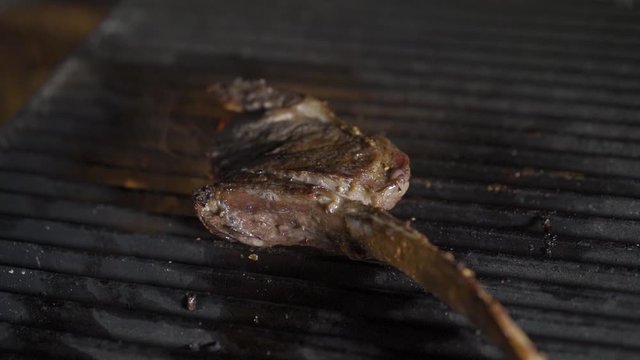 Single tomahawk rib steak on hot black grill. Fire and flames, steak on the grill.