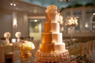 Five tier white and gold tuxedo wedding cake with fondant lace on caake stand
