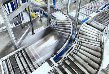 Transportation line conveyor roller with container in motion.