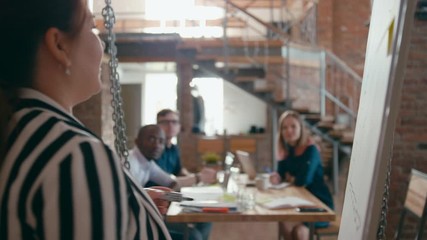 Female Asian Team Leader or Manager is Writing by Marker on White Flipchart Board in Office at Work Meeting or Business Presentation. Woman is Drawing Increasing Graph. 4K Corporate Medium Shot