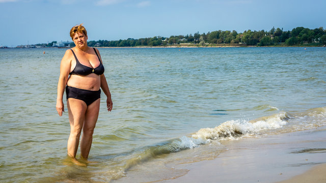 Mature plump woman sunbathing on the beach of the sea