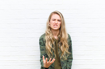 young blonde woman looking angry, annoyed and frustrated screaming wtf or what‚Äôs wrong with...