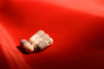 Cápsulas de gelatina con el numero 50 y en un fondo rojo