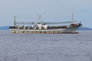 Squid fishing boat at anchor on coast and sky background. Fishing schooner equipped with lights to catch squid in the ocean.