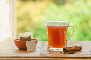 cup of tea with cinnamon with nature background, in a glass cup