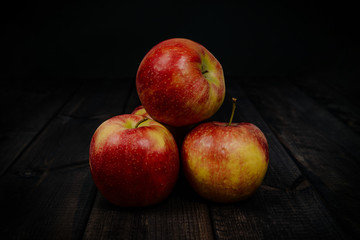 Red apples on a dark wooden table. The concept of eating fruit, eating meals with vitamins. Taking care of yourself, diet. Healthy food, apples.