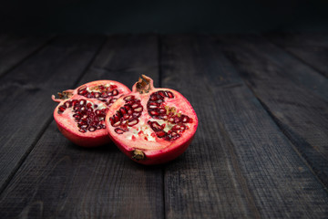 Pomegranate fruit on a dark wooden table. The concept of eating fruit, eating meals with vitamins. Taking care of yourself, diet. Eating exotic fruits.