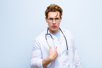 young red head doctor feeling confused, puzzled and insecure, pointing to self wondering and asking...