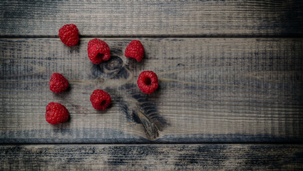 Raspberries on a dark wooden table. The concept of eating forest fruit. Healthy eating fruit, red raspberries. Supply of vitamins.