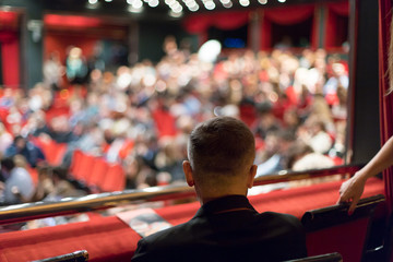 man watching theater audience arriving and taking seats before the performance
