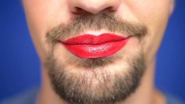 close-up. A bearded man with painted lips smiles sexually and blows a kiss.