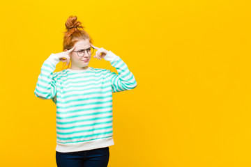 young red head woman looking concentrated and thinking hard on an idea, imagining a solution to a...
