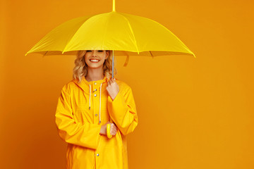 ng happy emotional girl laughing  with umbrella   on colored yellow background.