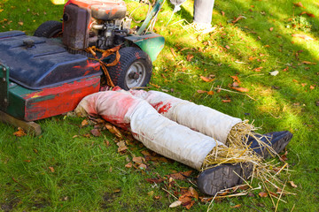 Concept: Halloween, bloody lawnmower, horror. Garden group: a straw doll is cut by a lawn mower.