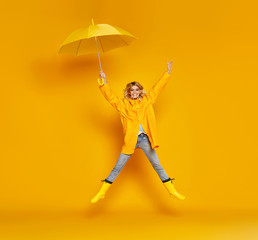 Fototapeta na wymiar young happy emotional girl laughing with umbrella on colored yellow background.