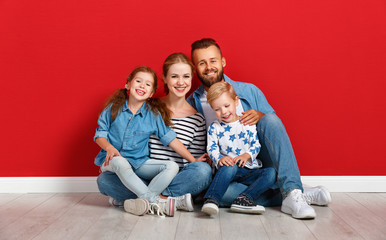 happy family mother father and children daughter and son  near an   red wall