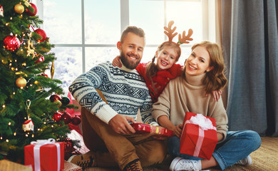 Obraz na płótnie Canvas happy family with gifts near Christmas tree at home.