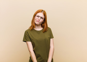 young red head pretty woman feeling confused and doubtful, wondering or trying to choose or make a...