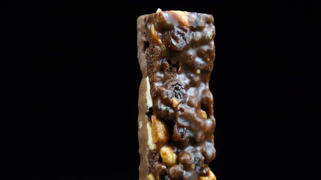Muesli covered in chocolate, healthy eating chocolate bar rotates on a black background.