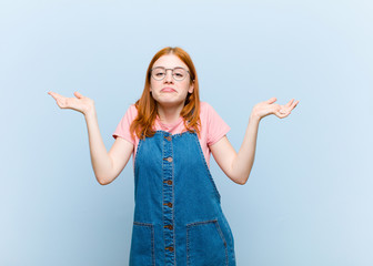 young red head pretty woman feeling puzzled and confused, doubting, weighting or choosing different...