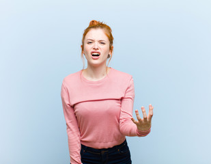 young red head pretty woman looking angry, annoyed and frustrated screaming wtf or what‚Äôs...