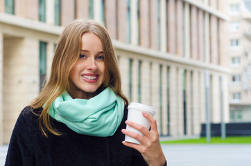 Cute redhead girl with braces is drinking coffee outside. correction of the bite with a metal...